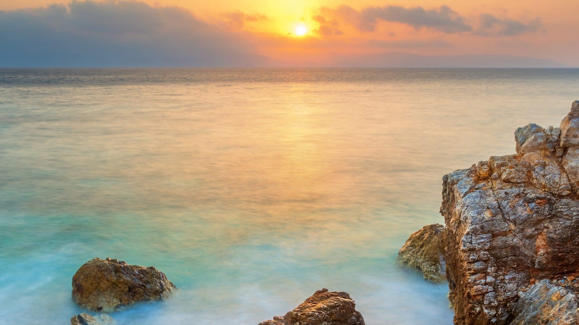 Drift beside Santorini’s caldera cliffs at sunset